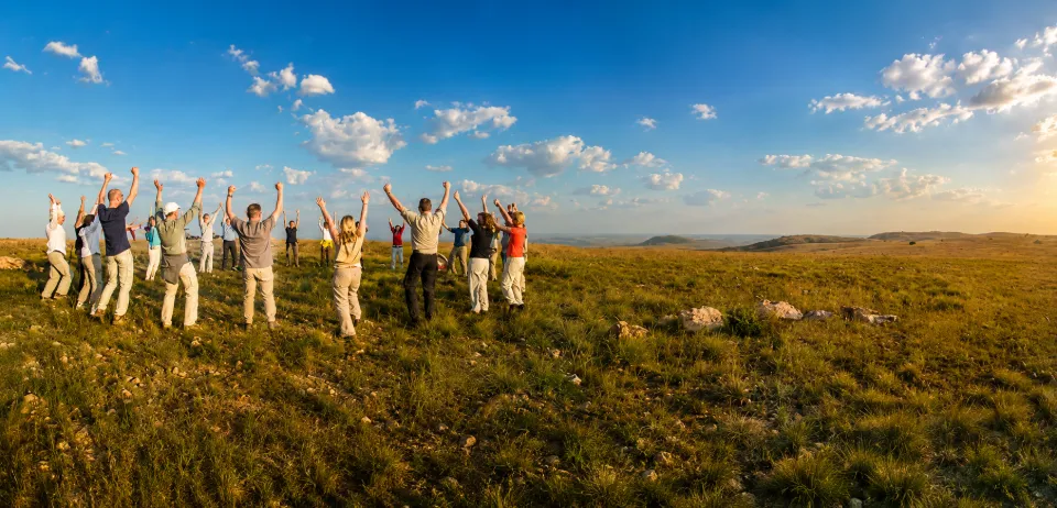 Group of people with raised arms standing in open grassland