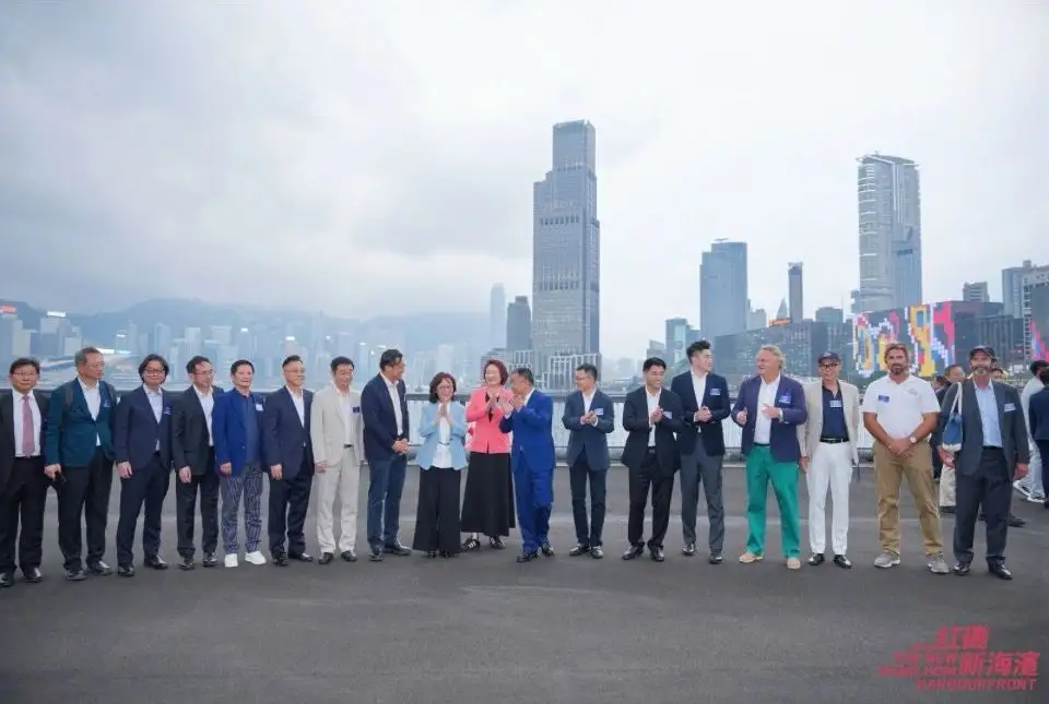Guests gathered for a group photo on the Hung Hom waterfront, with the Hong Kong skyline behind them