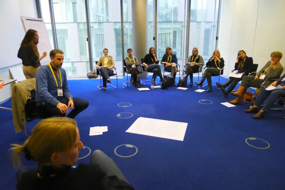 Small group seated in a circle on a blue carpet