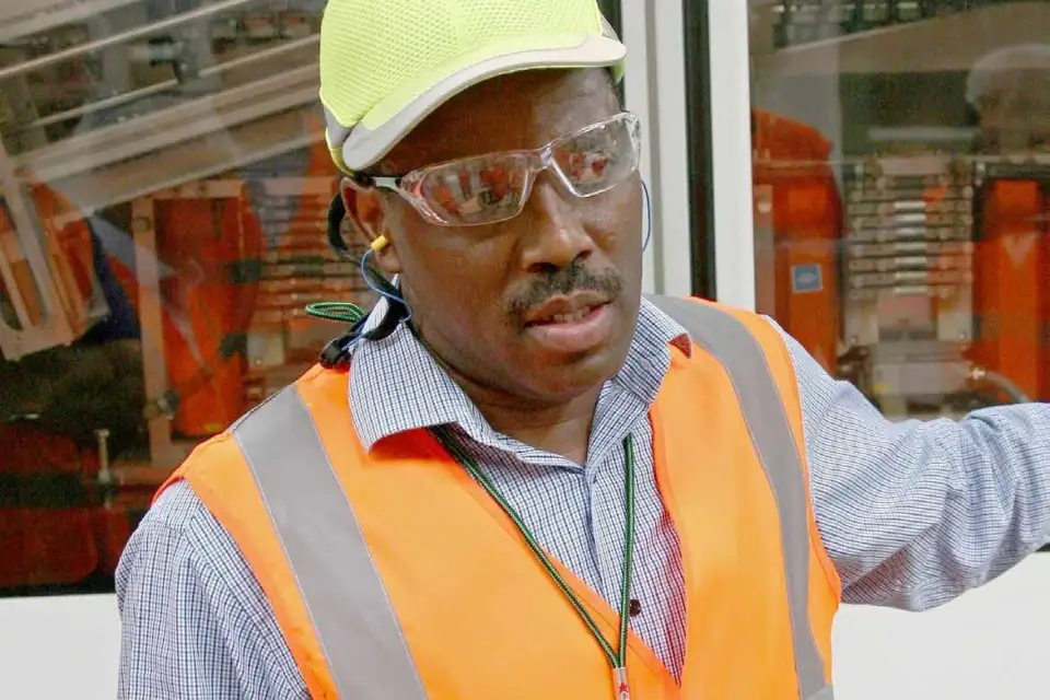 Team leader in a hard hat and safety vest explaining on the plant floor