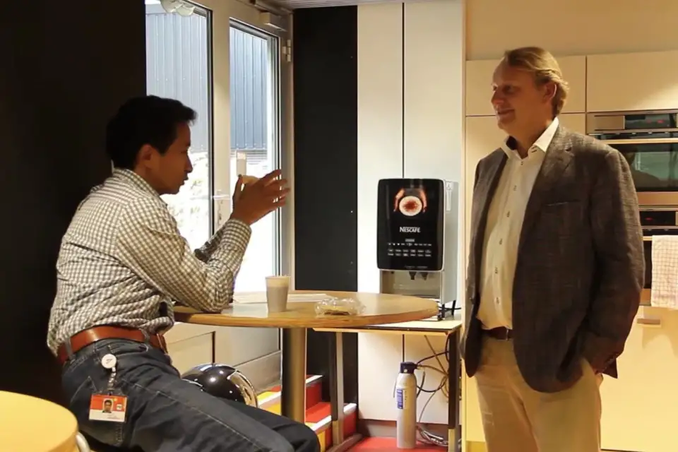 Two colleagues in conversation beside a high table in a bright office