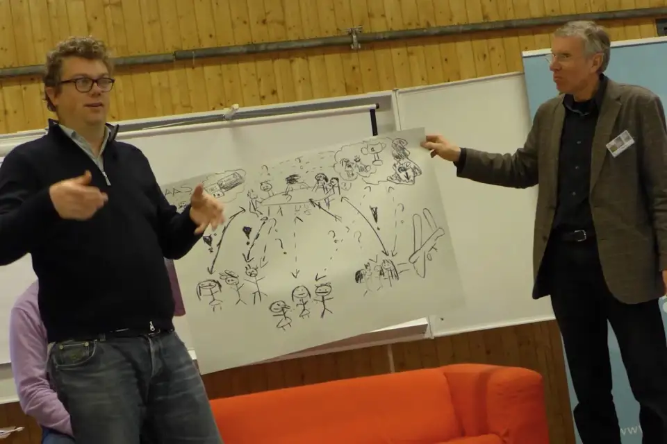 Facilitator explaining a hand-drawn diagram on a flip chart to a colleague