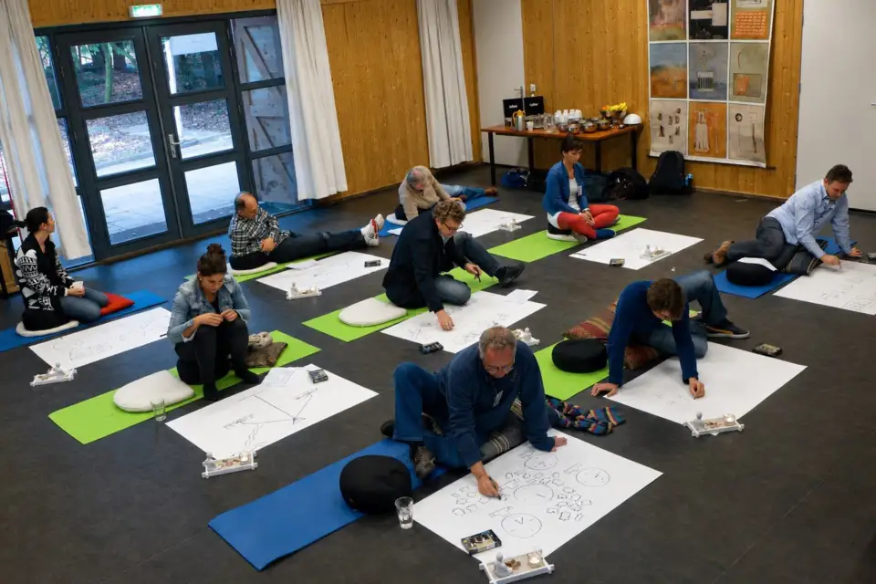 KLM participants kneeling on mats, drawing on large sheets of paper