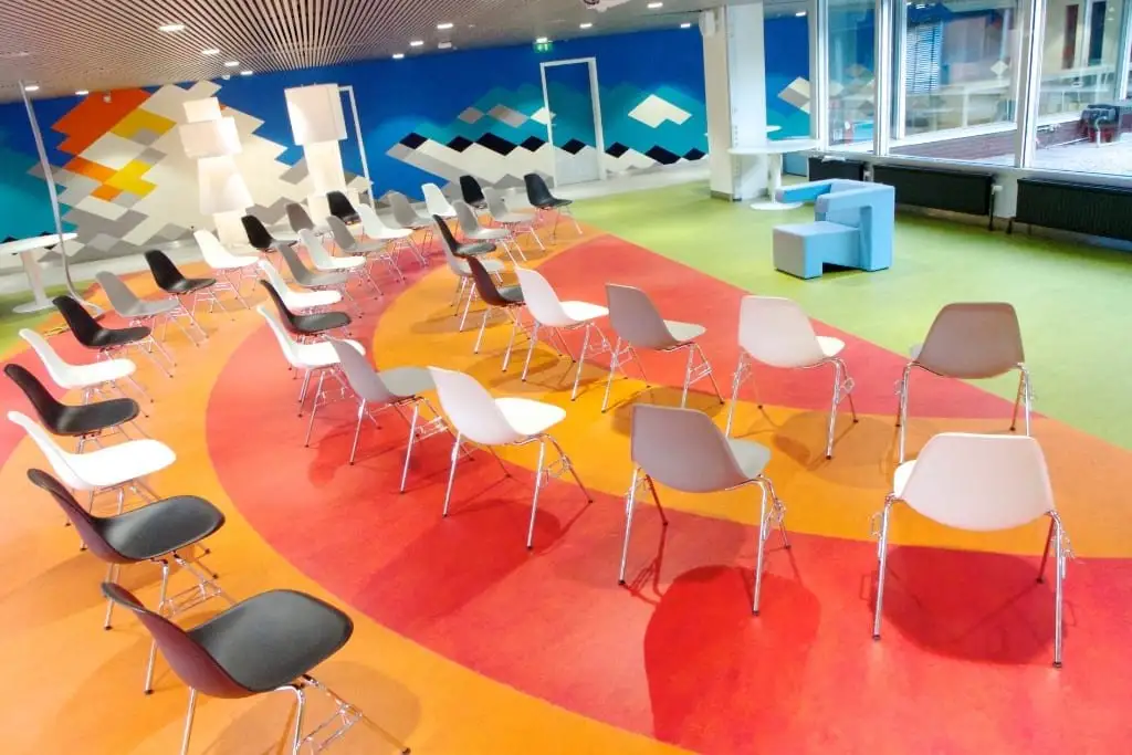 The Kgotla Workplace at KLM, with a colourful floor and white chairs
