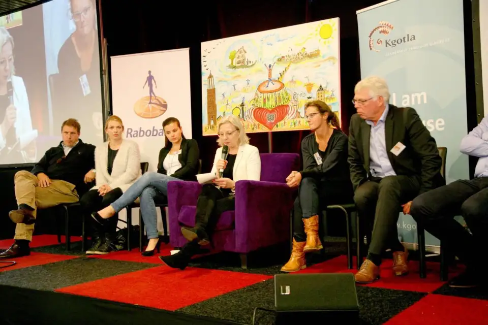 Panel seated on a purple sofa on stage beside a Rabobank banner