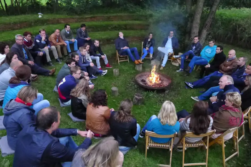 Participants seated in a circle around a campfire outdoors