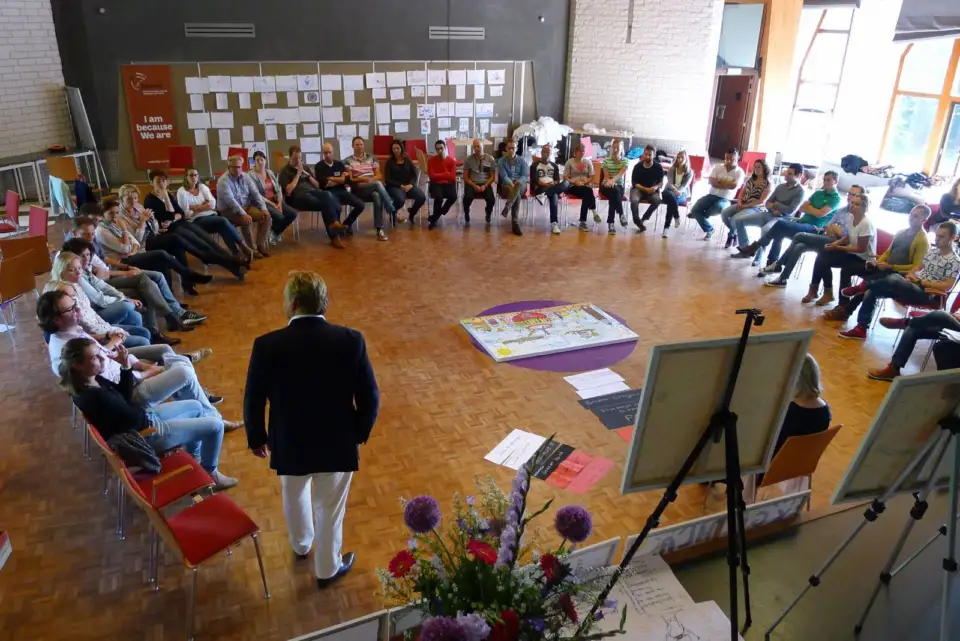 Facilitator standing in a large circle of seated participants