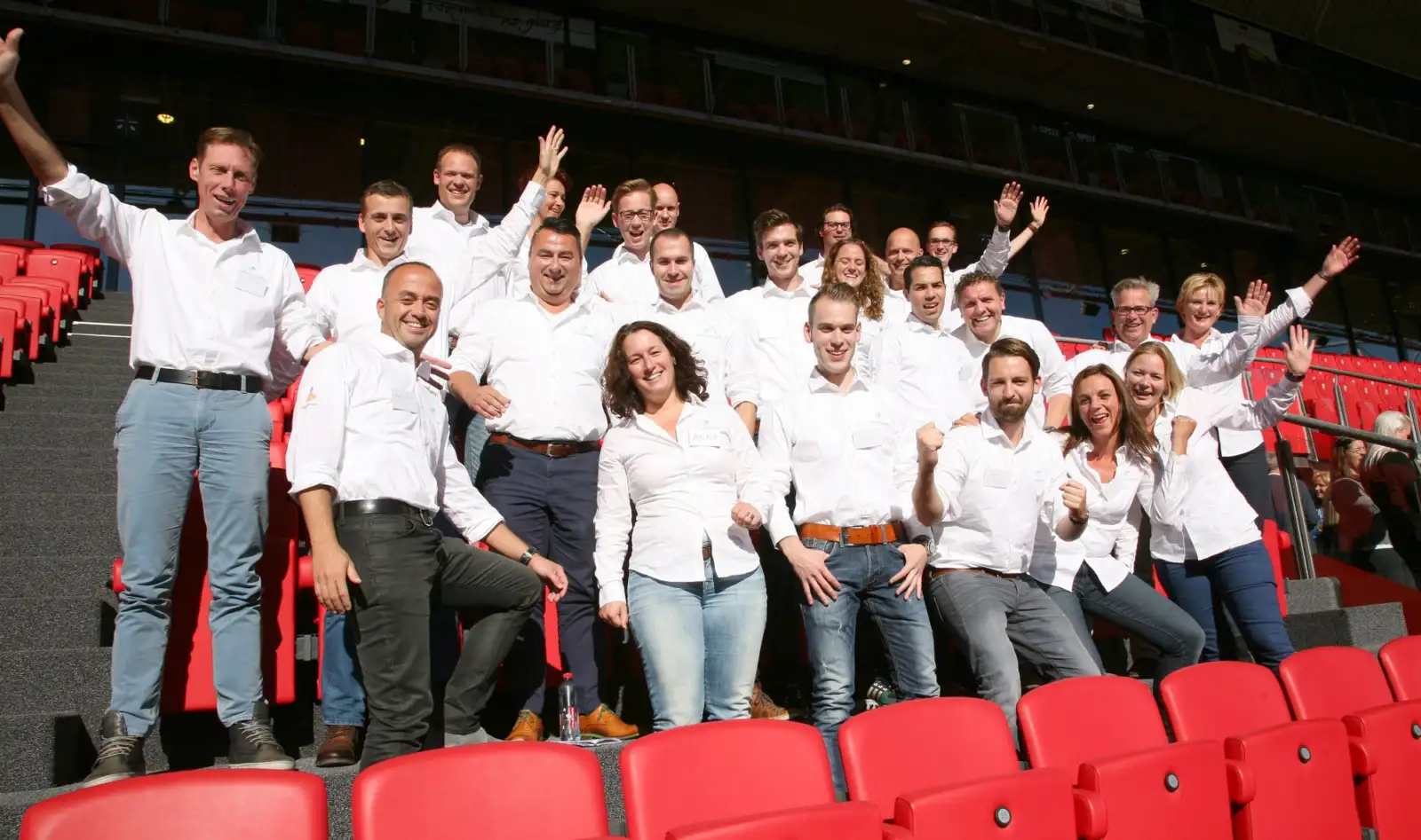 Group of employees in white shirts cheering in an auditorium