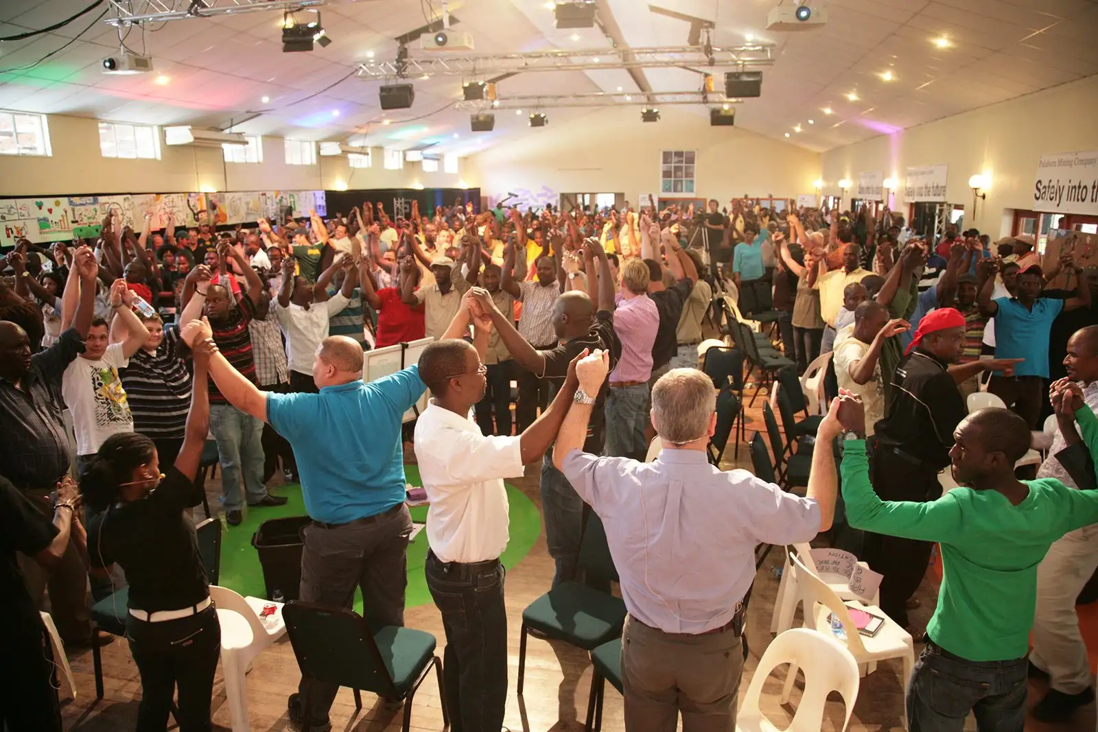Large group of participants standing with raised arms in a hall