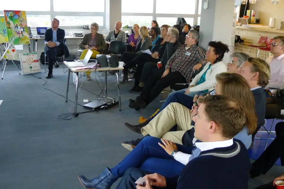 Participants listening in a circle of chairs in a bright meeting room