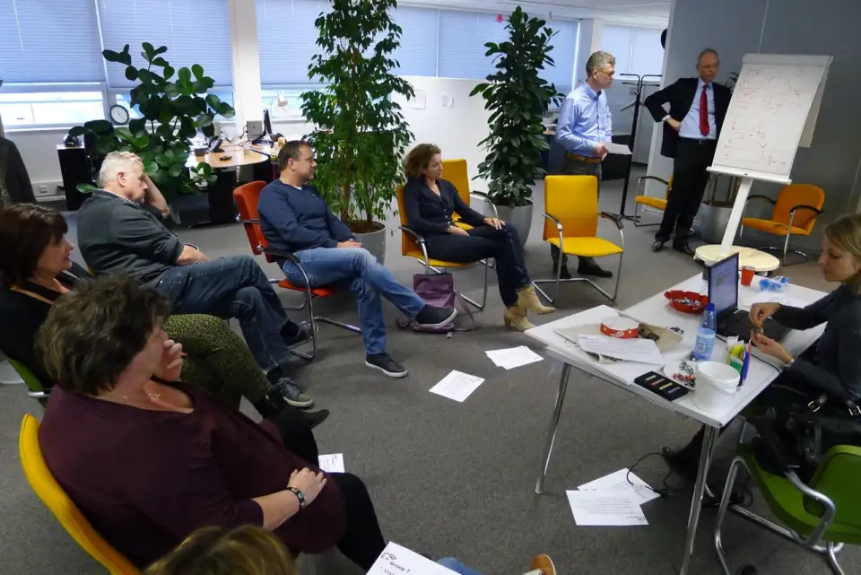 Participants in a circle of chairs around a flip chart