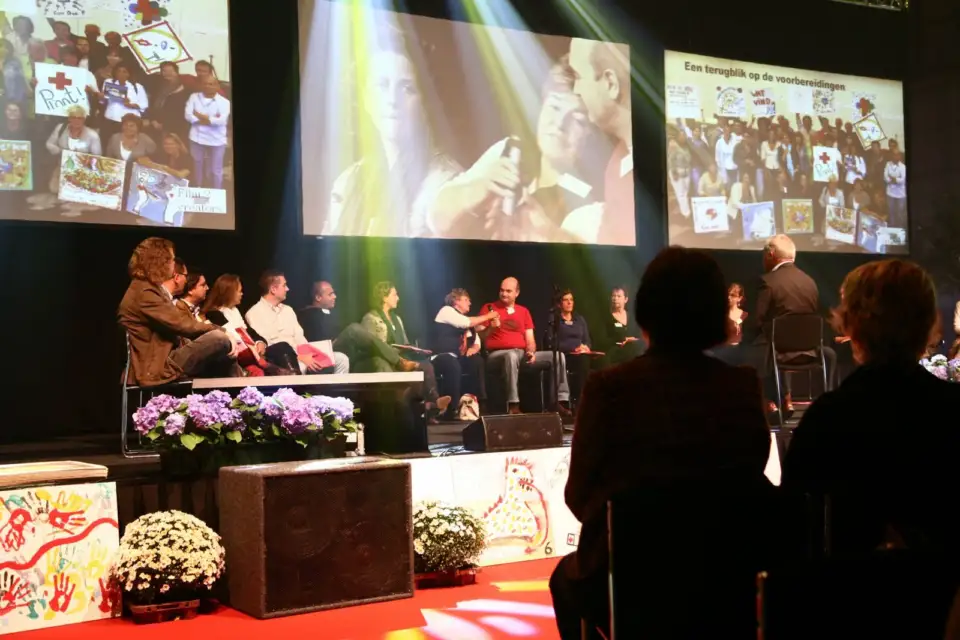 Panel on a stage under large screens, with flowers in front