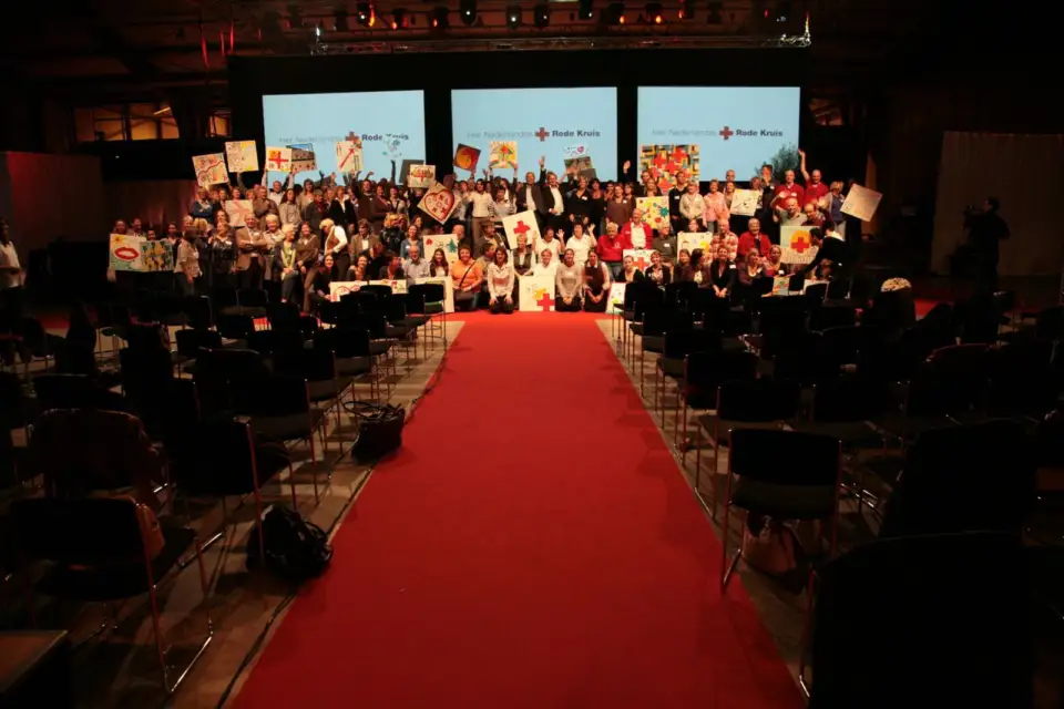 Audience seated on both sides of a red carpet facing the stage