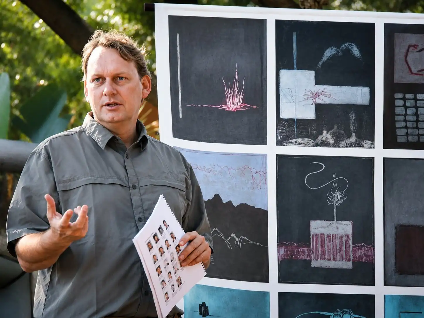 Facilitator holding a booklet in front of a wall of artworks