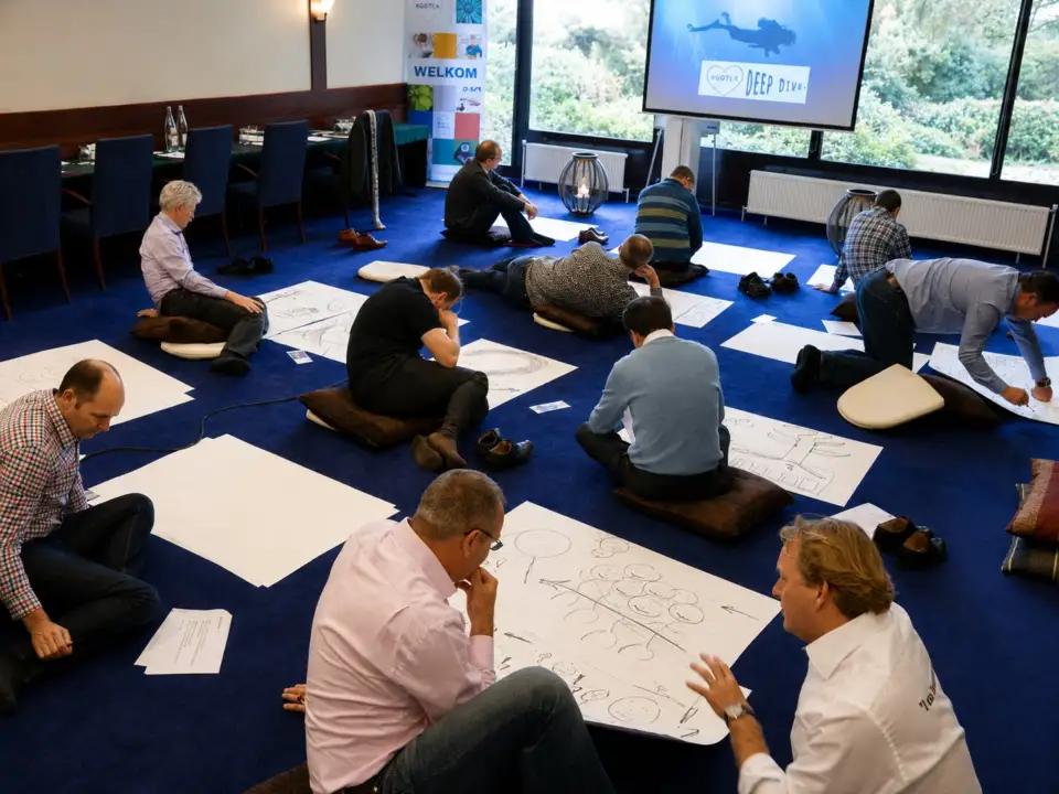 Participants drawing on large sheets of paper on the floor of a meeting room
