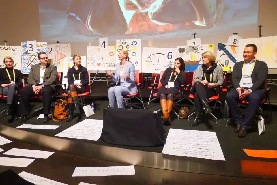 Participants seated in a circle around artworks laid out on the floor