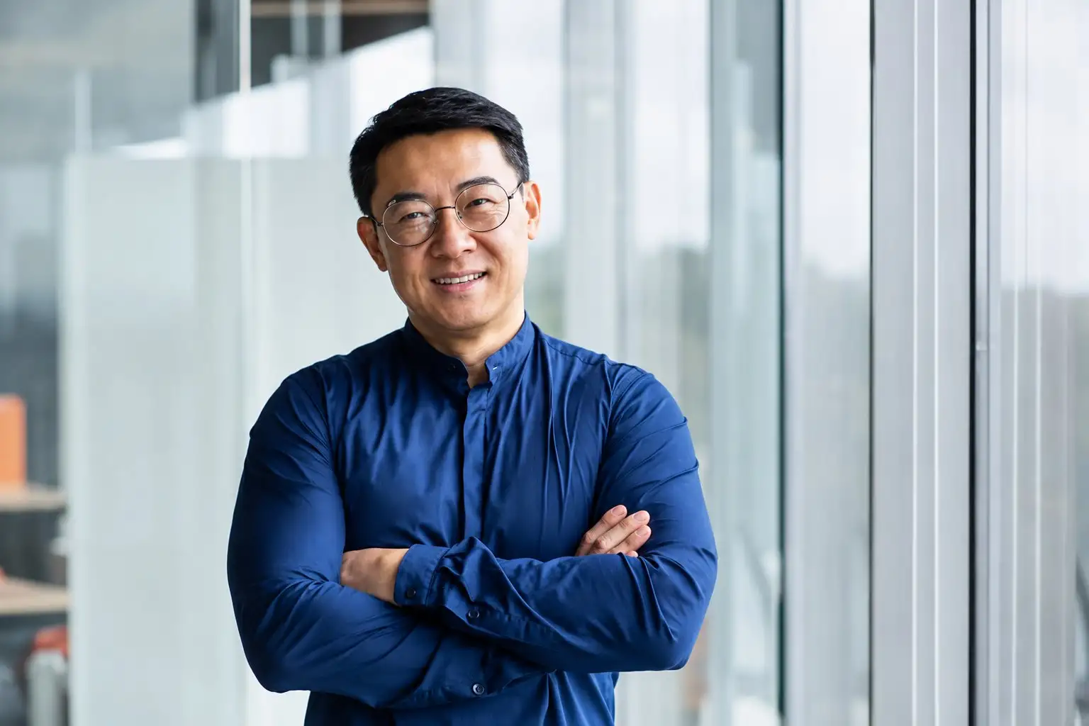 Business leader with arms folded in a bright office